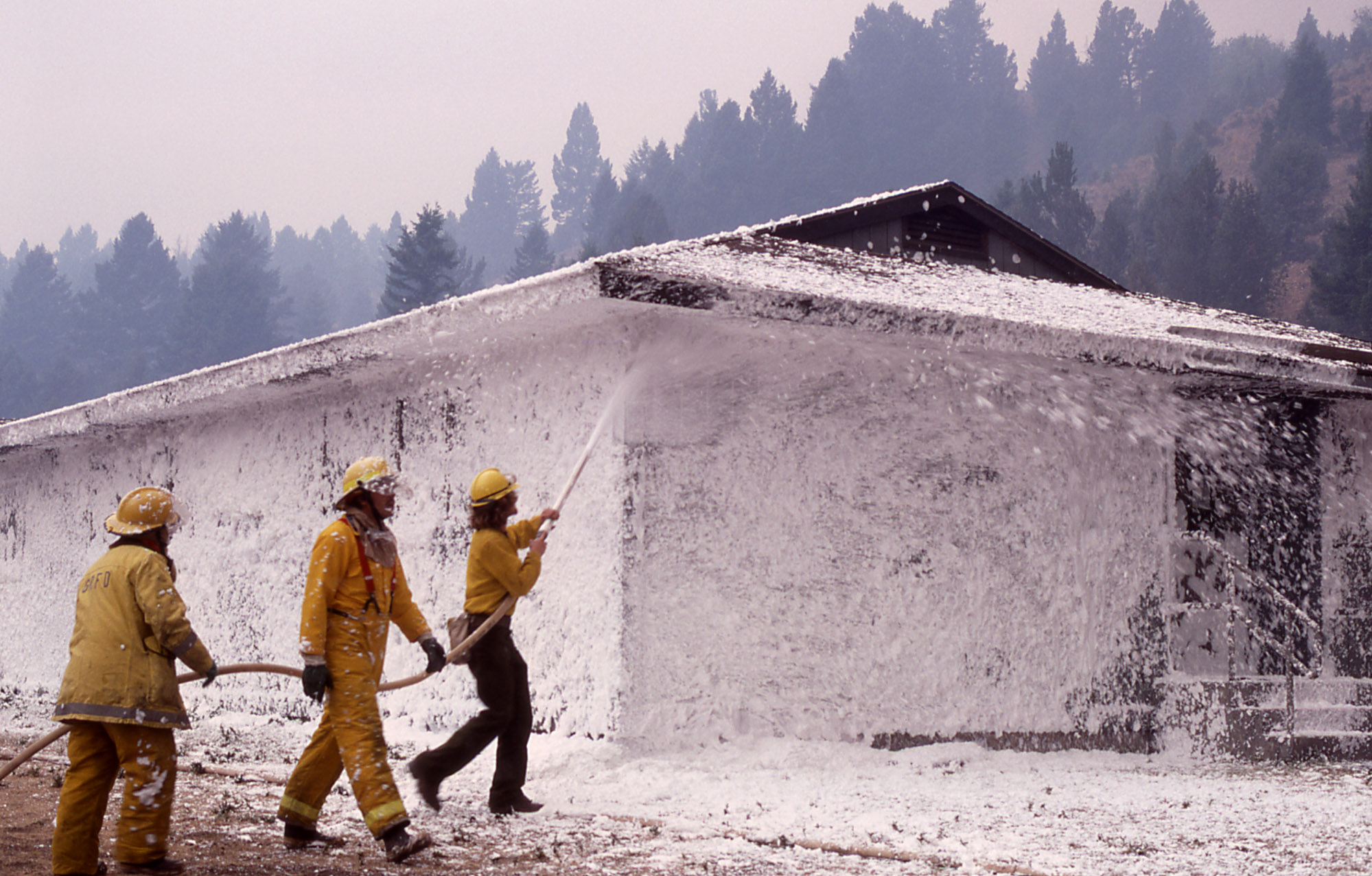 firefighters spraying foam on a building