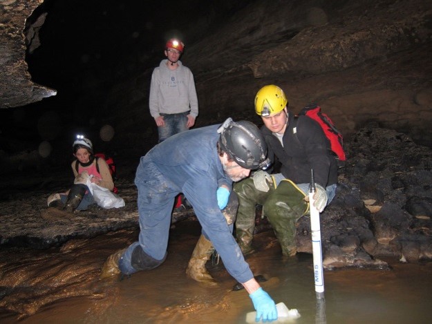 scientists wearing waterproof gear and hard hats take water samples and quarter quality field measurements in a cave scientists wearing waterproof gear and hard hats take water samples and quarter quality field measurements in a cave