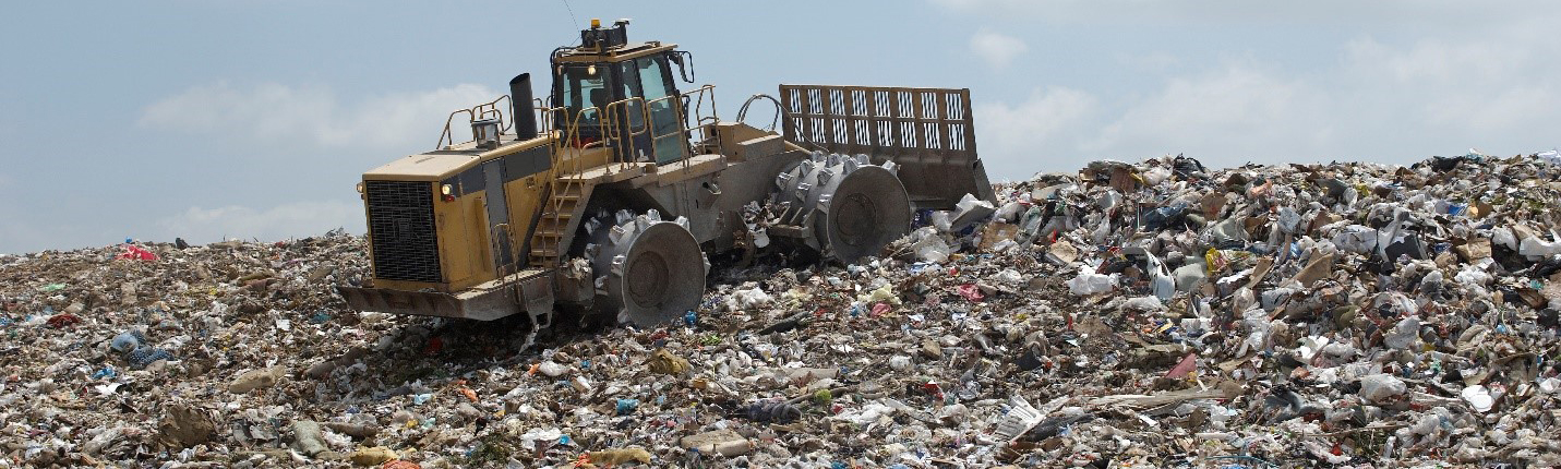 tractor pushing trash around on a gigantic trash pile in a landfill