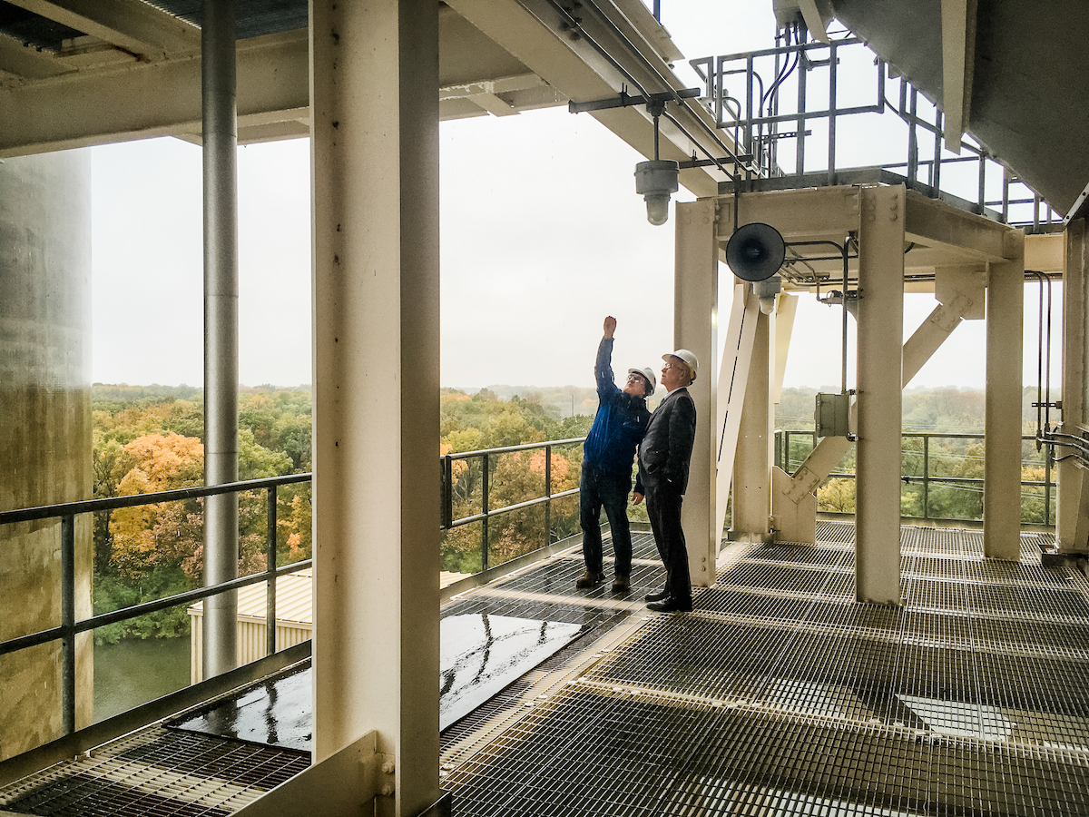 OBrien and Killeen stand on industrial platform. OBrien is pointing up showing Killeen something. Killeen is looking up.